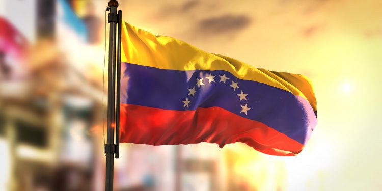 Venezuela Flag Against City Blurred Background At Sunrise Backlight